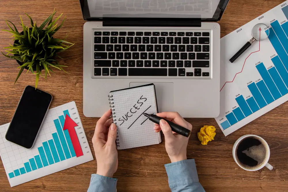 Notebook with 'SUCCESS' on a desk with account payable management charts