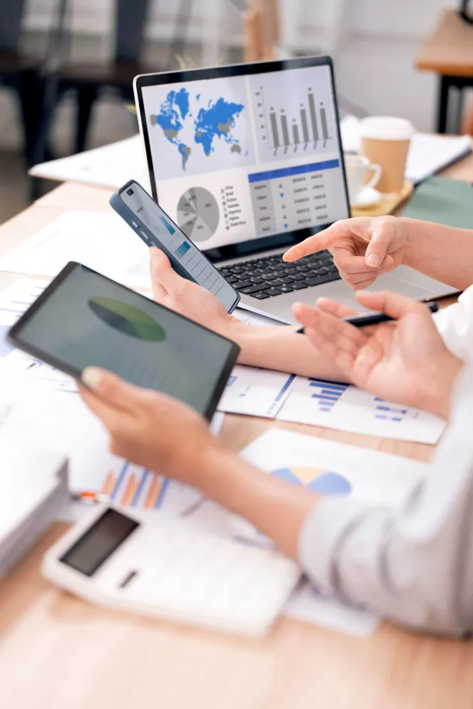 Business professionals analyzing financial data on laptop and mobile for advisory services.