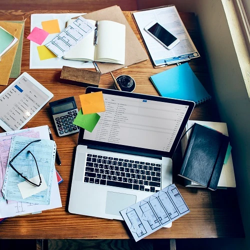 Cluttered bookkeeping desk with laptop, calculator, and financial records for small business