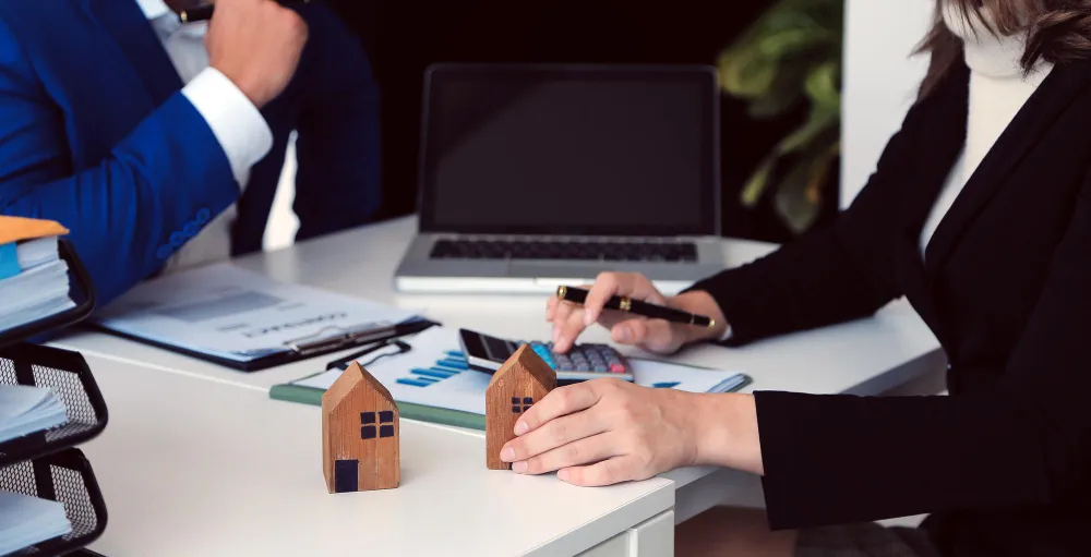 Real estate bookkeeping professional analyzing financial data with mini house models