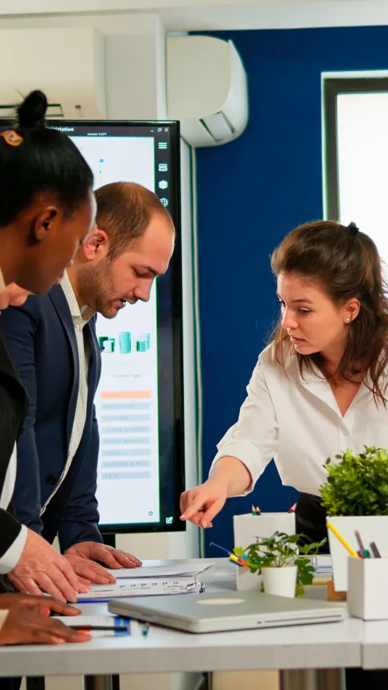 Team collaborating over documents with charts on screen in modern office